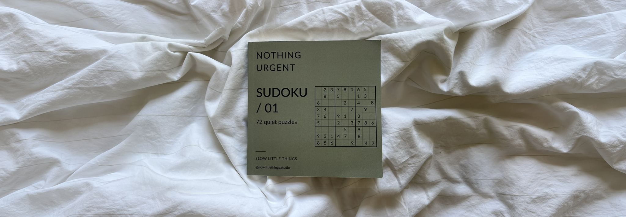 Nothing Urgent Sudoku book resting on rumpled bedding